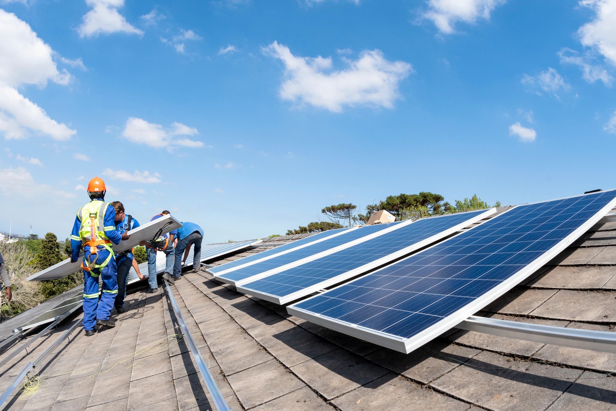 Workers installing a solar panel on a roof
